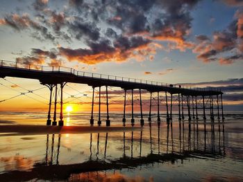 Silhouette pier over sea against sky during sunset