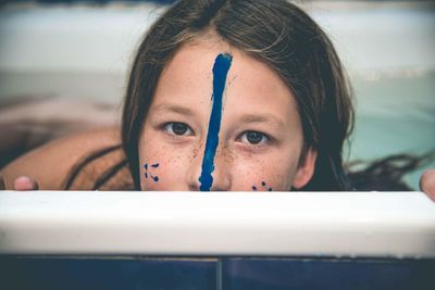 Close-up of sad girl with face paint in bathroom