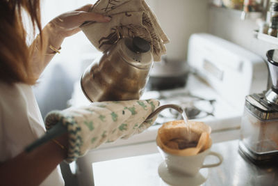 Cropped image of woman pouring tea in cup at home