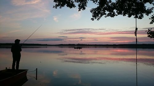 Silhouette of man fishing at sunset