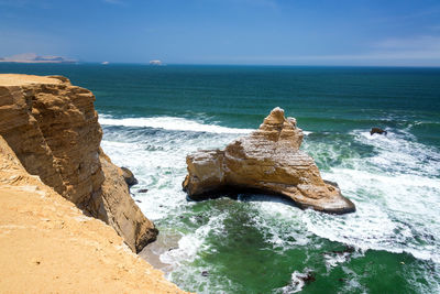 High angle view of rocky beach against blue sky
