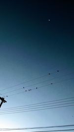 Low angle view of silhouette birds flying against clear sky