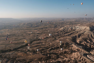 Aerial view of hot air balloons flying over dramatic landscape