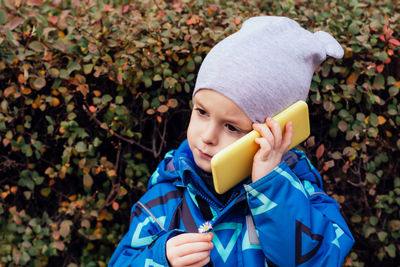 Portrait of a child with a phone in his hands, who looks to the side. childhood communication