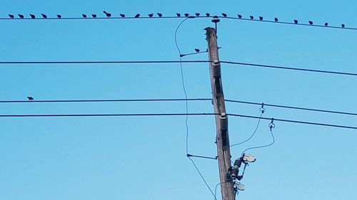 Low angle view of electricity pylon against blue sky