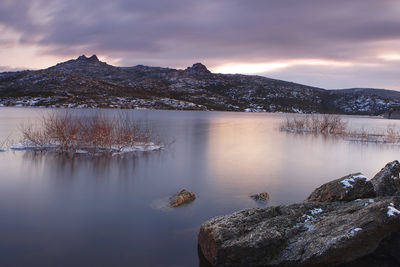 Scenic view of lake by snowcapped mountains against sky