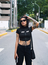 Portrait of young woman standing on road