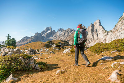 Woman hiking on footpath in alpine landscape in autumn, bischofsmütze, filzmoos, austria