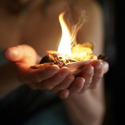 Close-up of hand holding burning candle