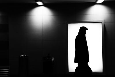Silhouette man walking against illuminated box at night