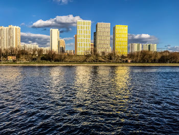 River by modern buildings against sky in city