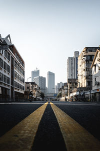 Surface level of road by buildings against clear sky