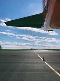Cropped image of airplane at airport runway against sky