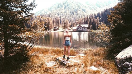 Rear view of man standing by lake in forest