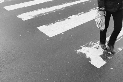 Low section of person crossing sign on road