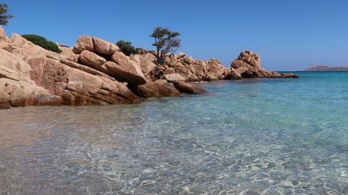 Rock formations in sea against clear blue sky