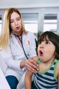 Female doctor examining girl back in hospital
