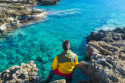 High angle view of man standing on rocks by sea