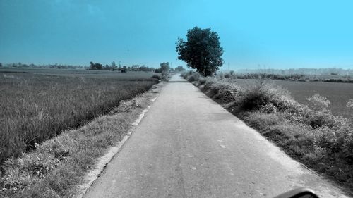 Surface level of empty road against clear blue sky