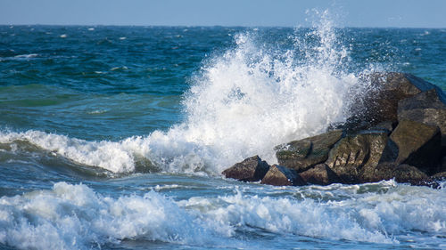 Waves splashing on sea against sky