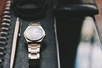 Close-up of wristwatch and smart phone on book 