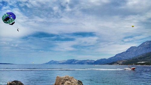 People paragliding over sea against sky