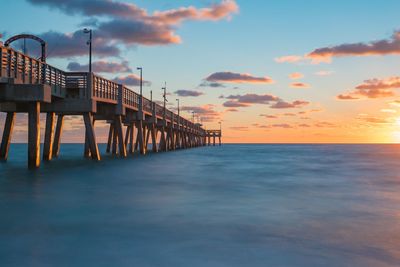 Pier over sea against sky during sunset