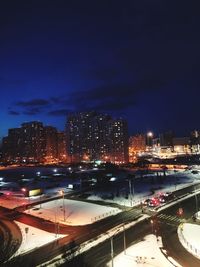 High angle view of illuminated street amidst buildings in city at night