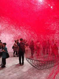 People standing by red umbrella against sky