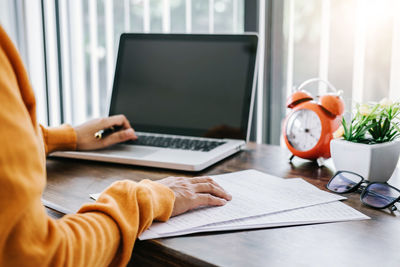 Midsection of man using laptop on table