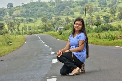 Portrait of woman sitting on road against trees