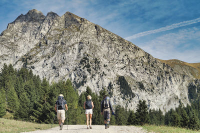 Rear view of people walking on mountain against sky