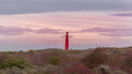 Lighthouse on street amidst buildings against sky