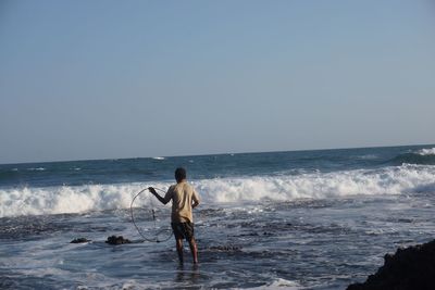 Full length of man standing on beach against clear sky