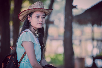 Thoughtful young woman wearing hat looking away outdoors