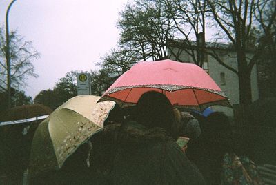 Rear view of woman holding umbrella against rain during rainy season