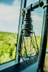 Close-up of light bulb hanging on railing