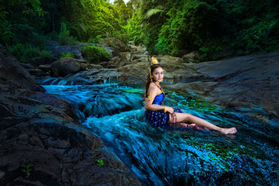 Young woman on rock in forest