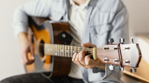 Midsection of man playing guitar