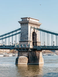 Bridge over river against sky in city