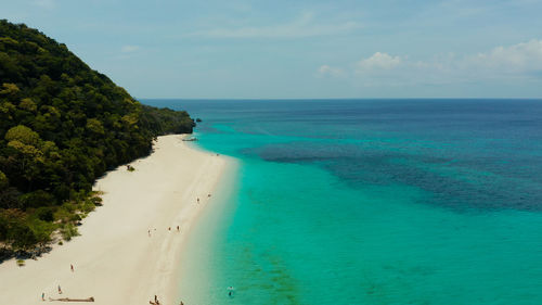 Coast with sandy beach with tourists and clear blue sea. puka shell beach. boracay, philippines.