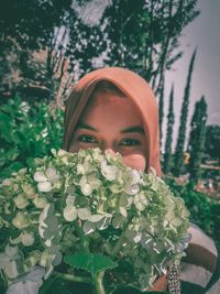 Portrait of beautiful young woman by flowering plants