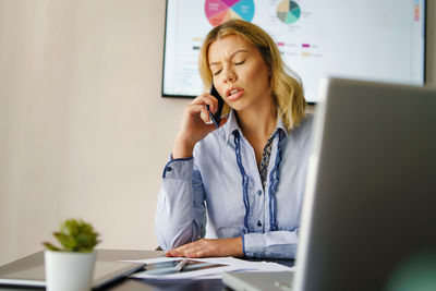 Mid adult woman using mobile phone while sitting on table