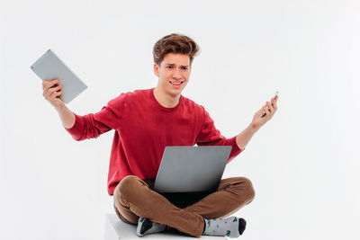 Portrait of smiling man holding smart phone against white background