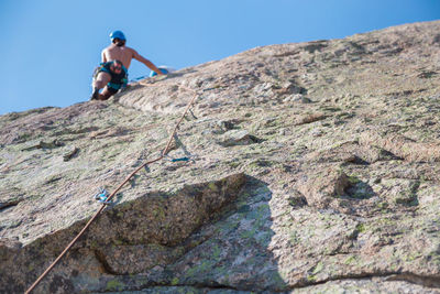 Low angle view of man on rock against sky