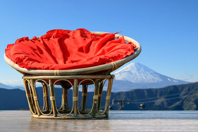 Chairs made of rattan and upholstery fabrics in red on wooden terrace with mount fuji background.