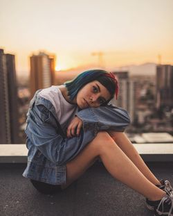 Portrait of young woman in city during sunset