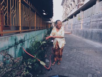 Mature woman watering plants at yard