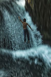 Rear view of man surfing in sea