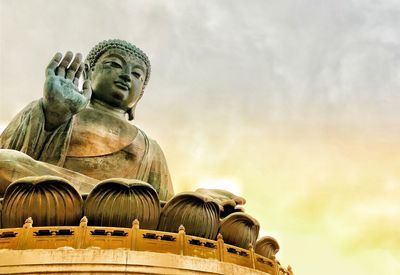 Low angle view of buddha statue against sky